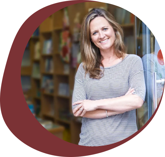 Smiling woman standing with arms crossed in a library.